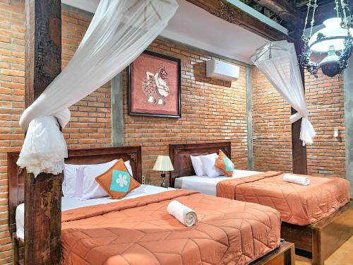 a bedroom with two beds and a brick wall at Ndalem Suryo Saptono Guest House in Yogyakarta