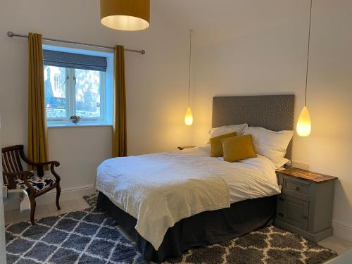 a bedroom with a bed and a chair and a window at Cornish Billys Barn in Penzance