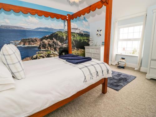 a bedroom with a bed with a painting of the ocean at Penholm in Penmaen-mawr