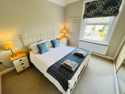 a bedroom with a bed with blue pillows and a window at RedButt House, Freshwater, 3 Bedrooms, WiFi, Garden in Freshwater