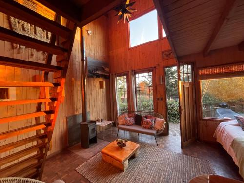 1 dormitorio en una cabaña de madera con 1 cama y 1 mesa en Punta Ballena Lodge, en Pichilemu