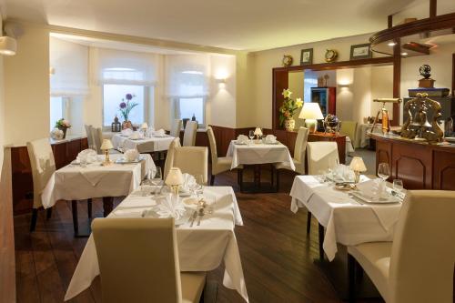 a dining room with white tables and white chairs at Villa Neptun in Heringsdorf