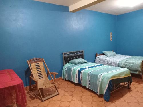 a bedroom with two beds and a chair and a table at Casa Huamanga in Ayacucho