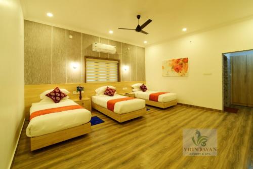 a bedroom with two beds and a ceiling fan at Vrindavan Resort and spa in Kokkānisseri