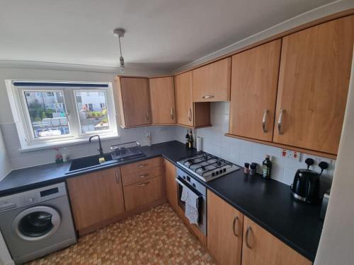 a kitchen with wooden cabinets and a stove top oven at Apartment with a view, perfect for breaks and WFH in Plymouth