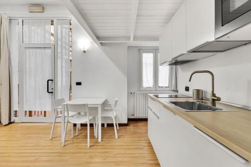 une cuisine avec des comptoirs blancs, une table et des chaises dans l'établissement Loft Margarita, à Milan