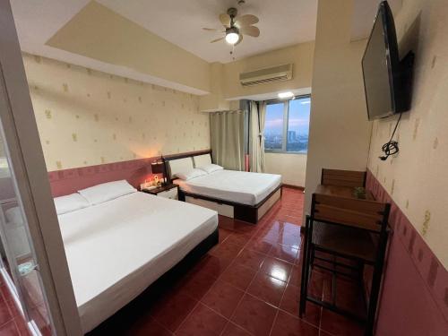 a hotel room with two beds and a television at Pearl Of The Orient Tower, in front of US Embassy in Manila