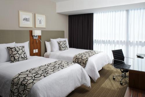 a hotel room with two beds and a desk at Casa Inn Premium Hotel Queretaro in Querétaro