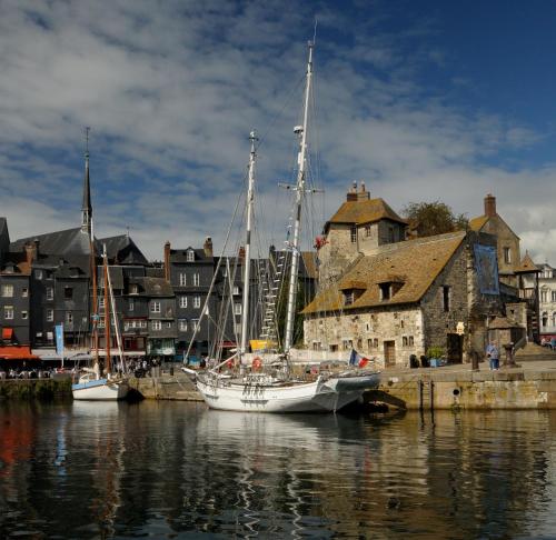 two boats are docked in the water near a city at Les Roulottes de la Risle in Calleville