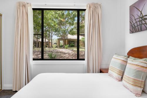 a bedroom with a bed and a large window at Leisure Inn Pokolbin Hill in Pokolbin