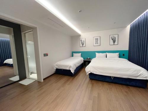 a hotel room with two beds and a mirror at GD Hotel in Yeosu