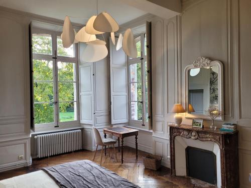 a bedroom with a fireplace and a bed and a mirror at Domaine des Longrais in Saint-Thurial