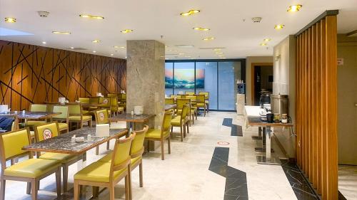 um restaurante com mesas de madeira e cadeiras amarelas em Turk Inn 2017 Otel em Ancara