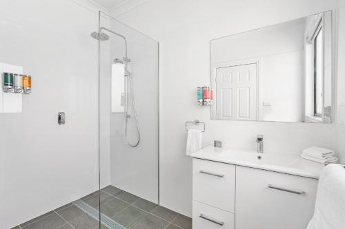 a white bathroom with a shower and a sink at Leisure Inn Pokolbin Hill in Pokolbin
