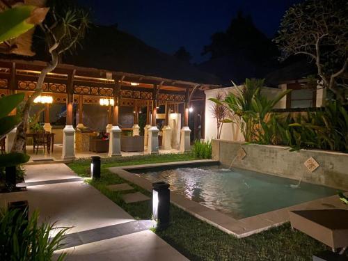 a pool in front of a house at night at Jimbaran BeachStroll Villa (2BR) in Jimbaran