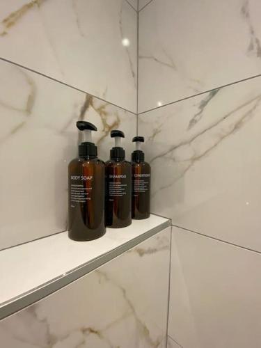 three shampoo bottles sitting on a shelf in a bathroom at The Golden white, Annecy in Annecy