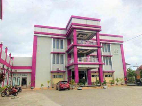 a pink and white building with a red car in front at MS Hotel Pinrang Mitra RedDoorz in Pinrang