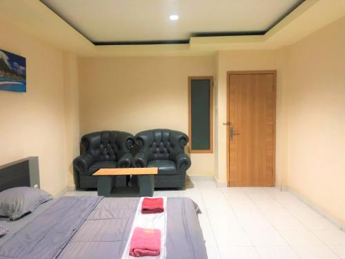 a living room with a black leather couch and a table at MS Hotel Pinrang Mitra RedDoorz in Pinrang