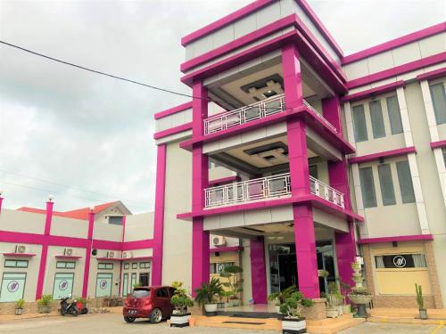 a pink building with a car parked in front of it at MS Hotel Pinrang Mitra RedDoorz in Pinrang