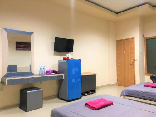 a room with two beds and a desk and a television at MS Hotel Pinrang Mitra RedDoorz in Pinrang