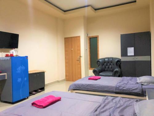a bedroom with two beds and a chair and a television at MS Hotel Pinrang Mitra RedDoorz in Pinrang