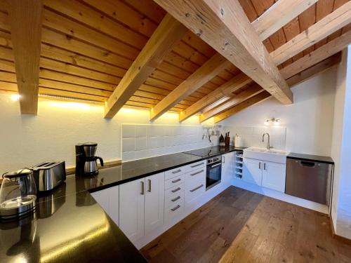 a large kitchen with white cabinets and wooden ceilings at Chalet Alpenflair in Pfronten