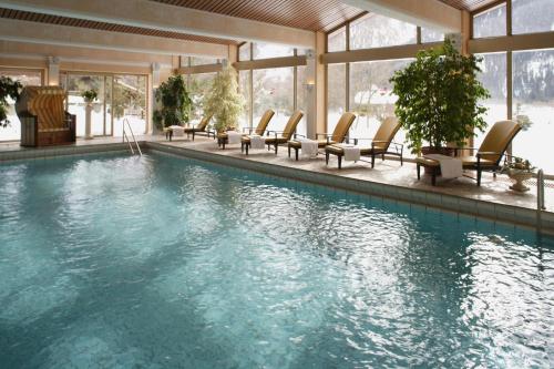a swimming pool with lounge chairs in a building at Alpenhof in Bayrischzell