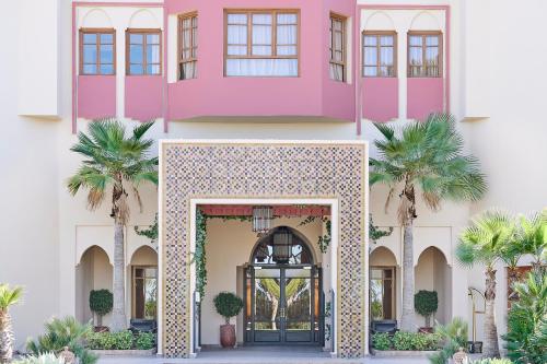a pink house with palm trees in front of it at Iberostar Waves Club Palmeraie Marrakech All Inclusive in Marrakech