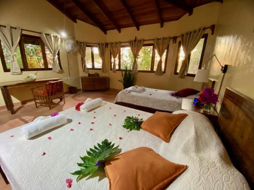 sypialnia z 2 łóżkami z kwiatami na łóżku w obiekcie El Mirador Glamping & Apartments & Woodhouse & Swimingpool w mieście Miramar