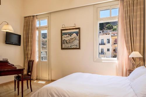 a hotel room with a bed and a desk and windows at Xenon Inn in Nafplio