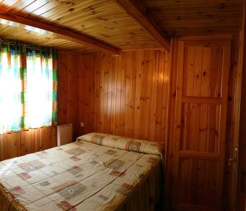1 dormitorio con 1 cama en una cabaña de madera en Càmping - Bungalows La soleia d'Oix, en Oix