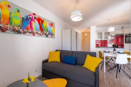 sala de estar con sofá gris y almohadas amarillas en Studio Cosy les Perruches, en Thonon-les-Bains