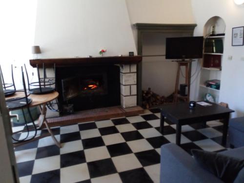 a living room with a fireplace and a checkered floor at Source AUGER in Gruchet-le-Valasse