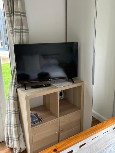 a flat screen tv on a wooden stand at The Old Beauty Room in Paulton