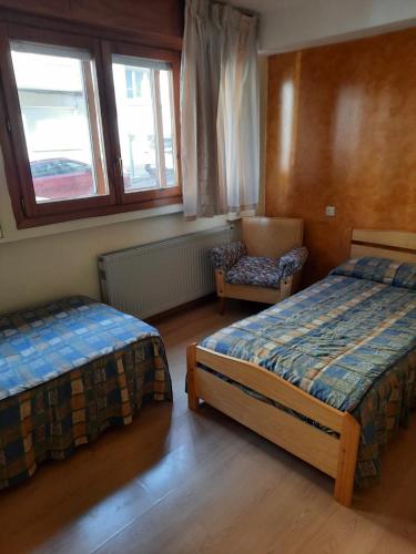 1 dormitorio con 2 camas, silla y ventana en HABITACIONES PENSION EL PARQUE, en Sabiñánigo
