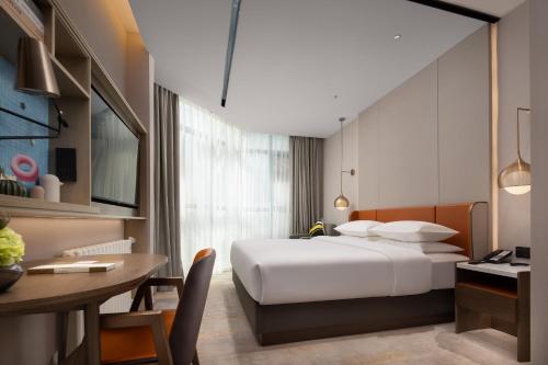 Home2 Suites By Hilton Wuhan Hankou Railway Station في ووهان: غرفة في الفندق بسرير ومكتب وطاولة