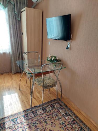 Ein Glastisch mit zwei Stühlen und ein Fernseher an der Wand in der Unterkunft Lushpy Apartment in Sumy