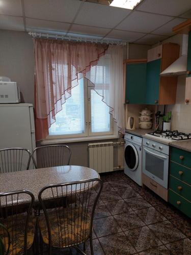 eine Küche mit Tisch und Stühlen und einem Fenster in der Unterkunft Lushpy Apartment in Sumy
