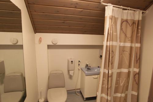 a bathroom with a toilet and a sink and a shower at Hotel Urkin Piilopirtti in Pinsiö