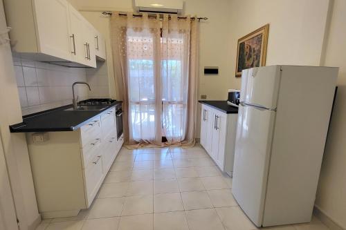 uma cozinha com electrodomésticos brancos e um frigorífico branco em Villetta Eliselena Best Vacation Ever em Villasimius
