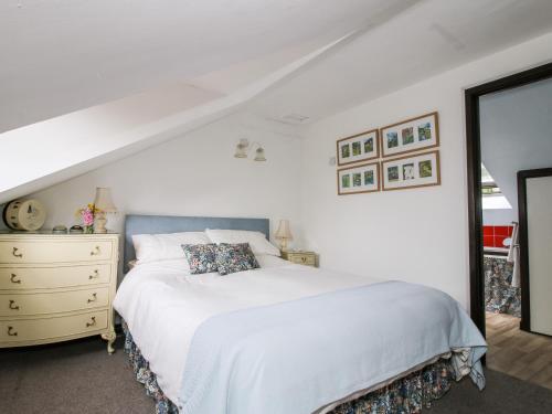 a white bedroom with a bed and a dresser at The Wheelhouse in Church Stretton