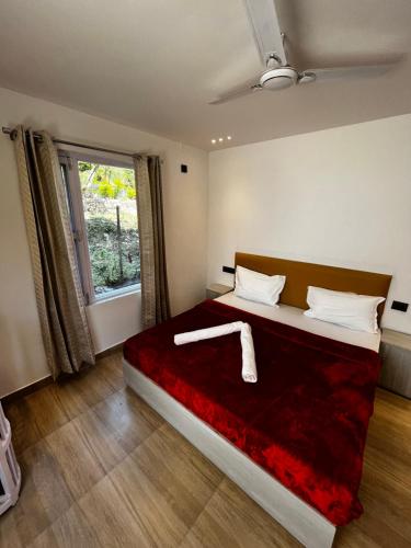 Un dormitorio con una cama grande con una manta roja. en The White House, en Rishīkesh