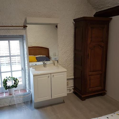 une salle de bain avec un lavabo, un miroir et un lit dans l'établissement Maison en bord de Loire, à Bou