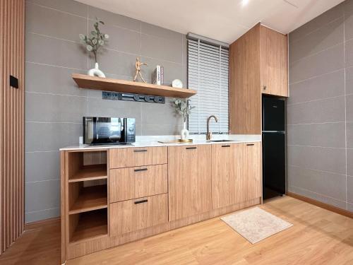 a kitchen with wooden cabinets and a microwave at SAMUA Homes (City View, Drawbridge & KTCC Mall) in Kuala Terengganu