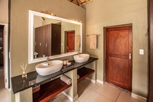 een badkamer met 2 wastafels en een grote spiegel bij Leopard's Lair Bush Lodge in Hoedspruit