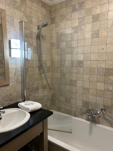 a bathroom with a shower and a tub and a sink at Hotel Atlas in Zeebrugge