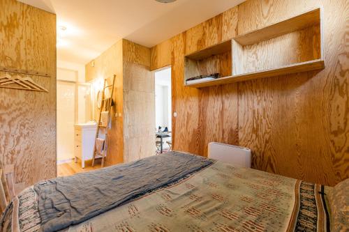 - une chambre avec un grand lit et des murs en bois dans l'établissement Appartement proche plage, à Lège-Cap-Ferret