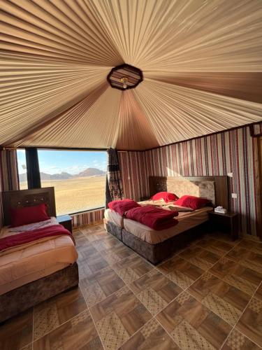 a bedroom with two beds and a large window at Wadi Rum Mars Camp in Wadi Rum