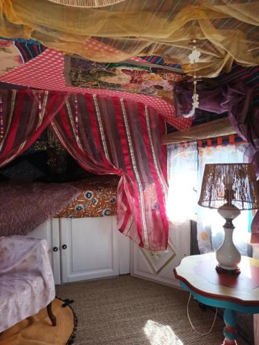 Zimmer mit einem Vorhang und einem Tisch mit einer Lampe in der Unterkunft Git'an Périgord la Bonne aventure in Groléjac