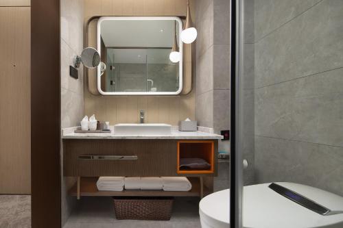 Home2 Suites By Hilton Wuhan Hankou Railway Station في ووهان: حمام مع حوض ومرآة ومرحاض
